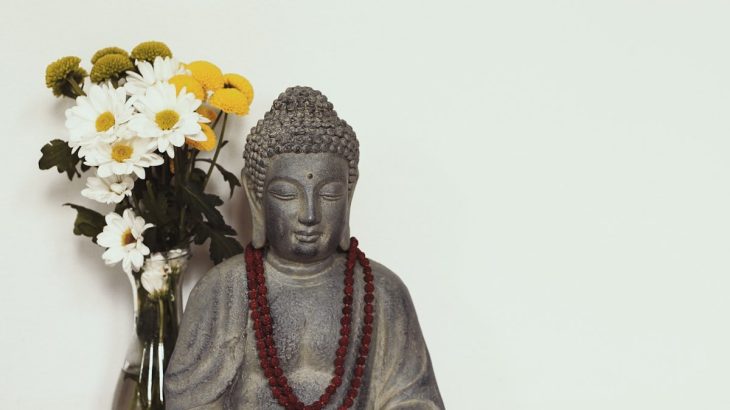 flower in vase near buddha figurine